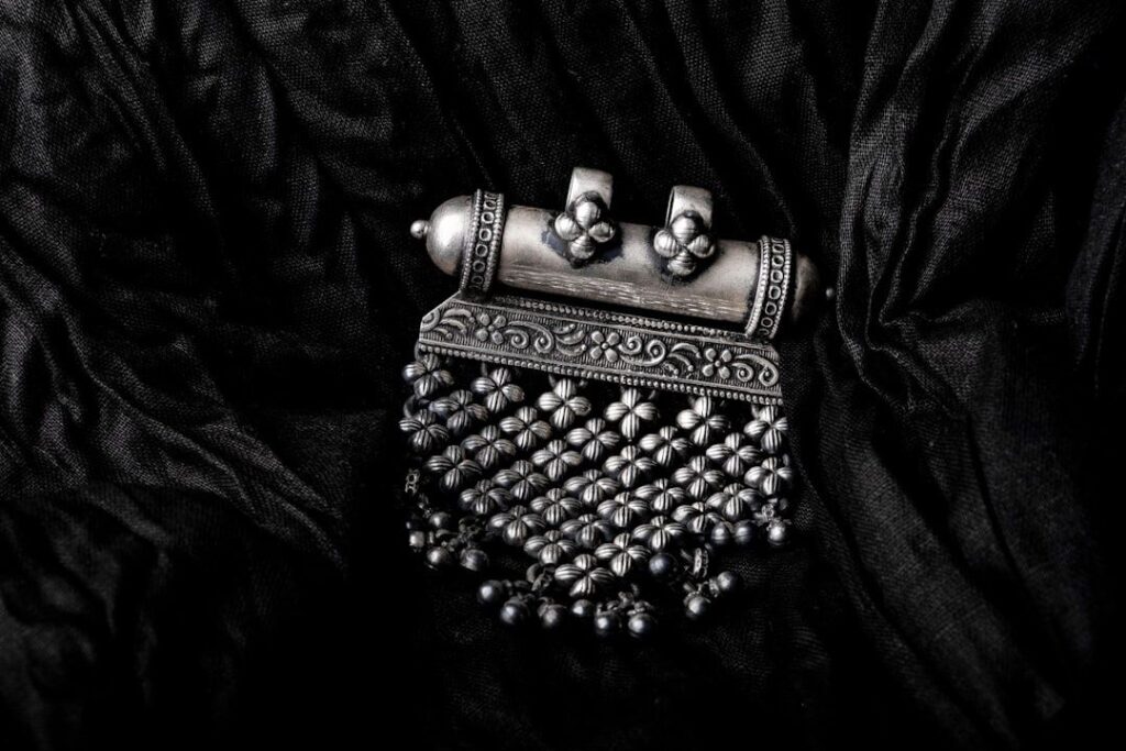Närbild av antikt silverhänge med detaljerad ornamentik och patina