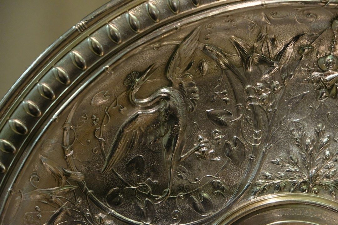 Närbild av antikt silver med fågelmotiv, ornament och mörk patina